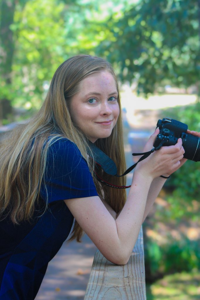 A woman smiling while holding a camera