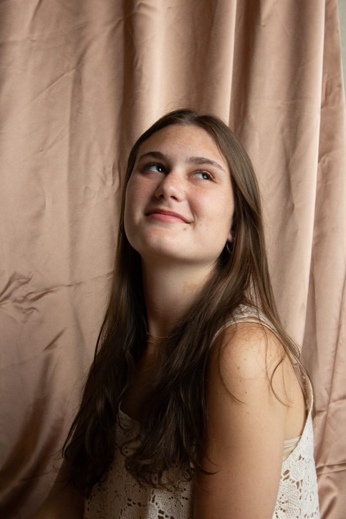 A woman smiling with a pink background