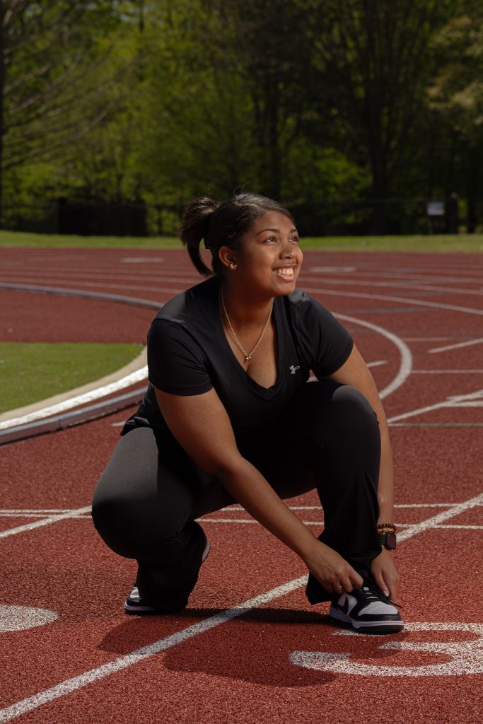 A woman smiling on a track field while tying her show